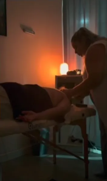 Sala de massagem com luz baixa e a Andreia junto da marquesa